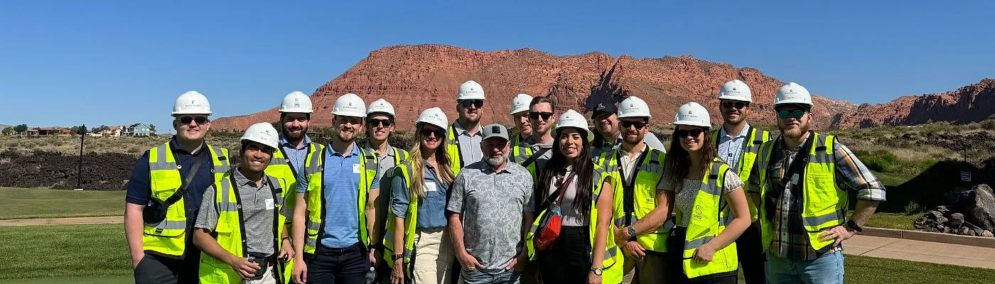 Stetson Blackmore with ULI Utah members in hard hats and safety vests on a site tour beneath the red cliffs of Washington County